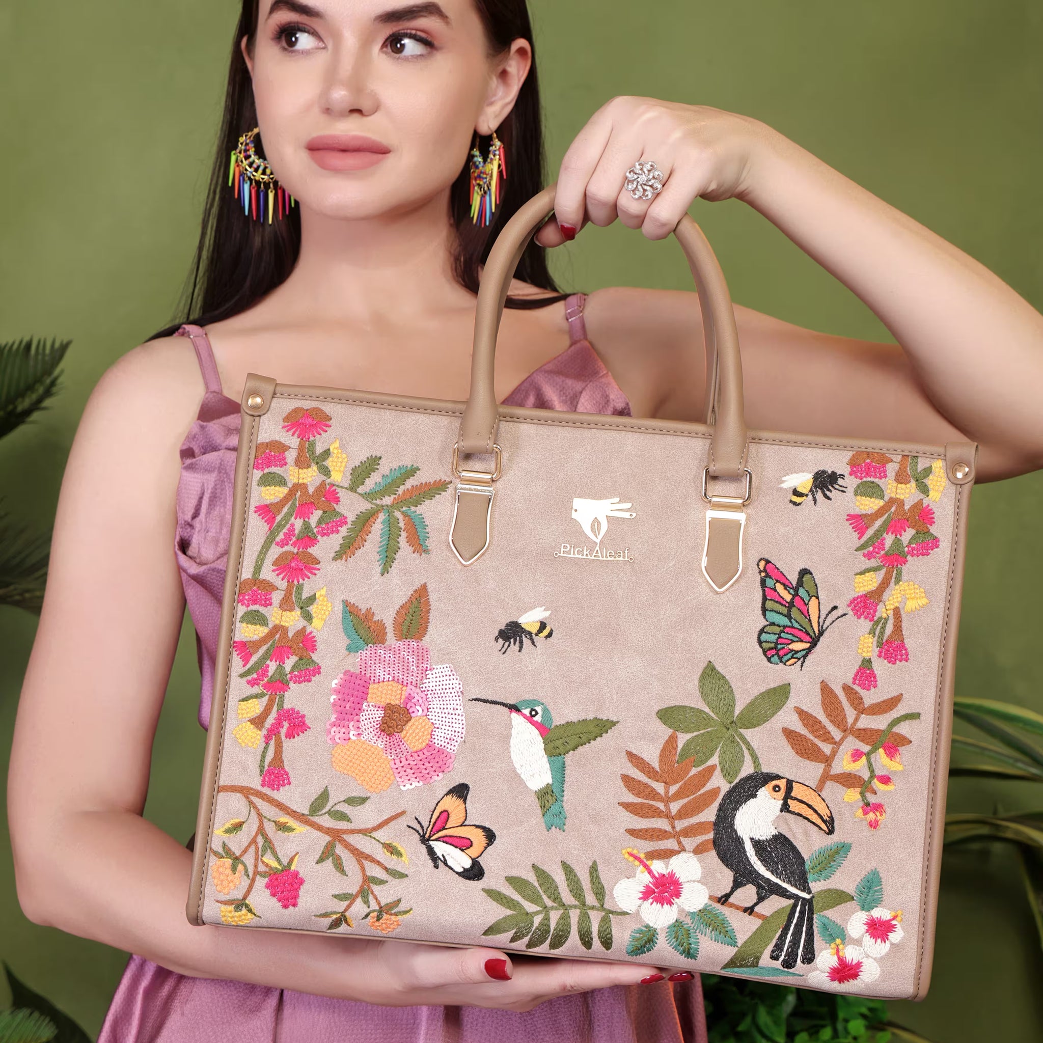 Woman holding a floral and bird-patterned handbag against a green background